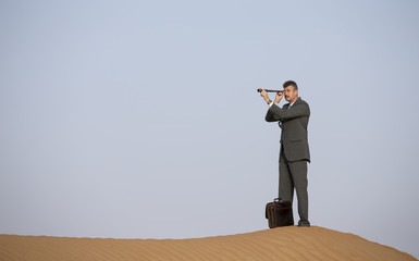 man in a suit in a desert with a spyglass