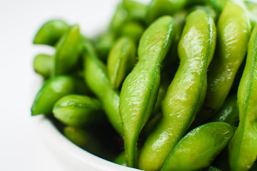 Closeup of green beans in white bowl on a white background