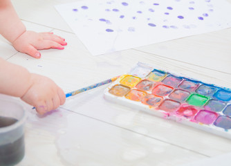 paint and a brush in the hands of a child.