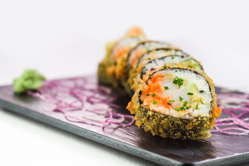 Traditional japanese rolls and sushi on a black stone plate and white background
