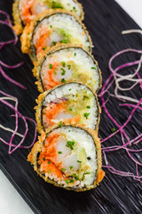 Traditional japanese rolls and sushi on a black stone plate and white background