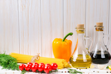 Spaghetti, tomatoes cherry, olive oil, herb and spices on old white wooden background. Set for healthy foods. Ingredients for salad.