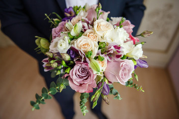 A wedding bouquet in the hands of the groom