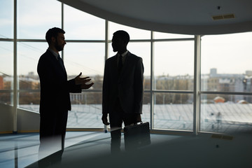 Elegant businessmen interacting in hall of office center