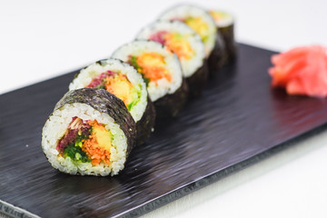 Vegetarian rolls and sushi on a black stone plate. Top view