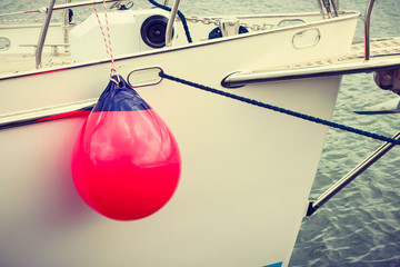 Sailboat in the sea with red fenders buoy.