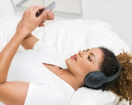Woman listening to music and looking at smartphone with worried expression