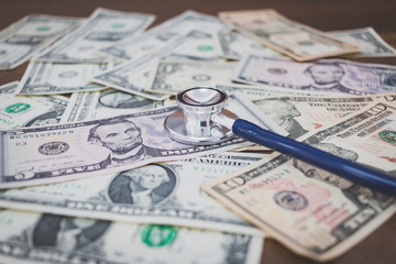Stethoscope on dollar banknote money on wooden background