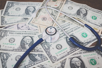 Stethoscope on dollar banknote money on wooden background