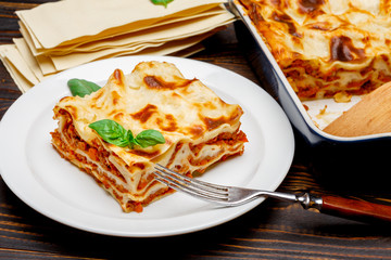 Portion of tasty lasagna on wooden backgound