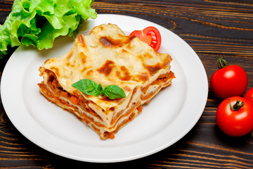Portion of tasty lasagna on wooden backgound