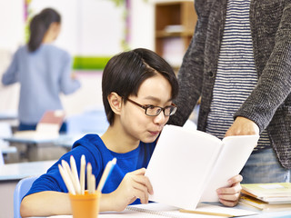 asian pupil getting help from teacher