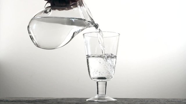 Water is poured into a glass beaker. White background.