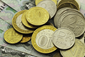 A handful of Russian coins of different denominations against the background of one thousand bills