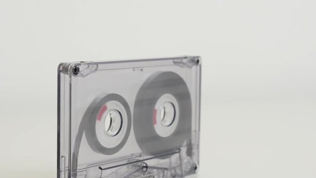 Compact audio cassette on white background 4K 2160p 30fps UltraHD tilting footage - Transparent analogue magnetic tape slow tilt 3840X2160 UHD video