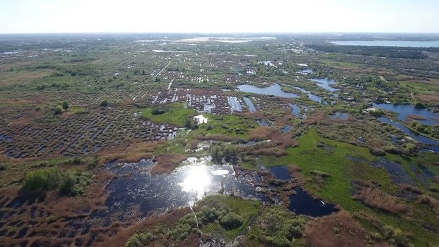 Splendid aerial shot of the Dnipro river basin with its little islets, curvy hook with indented coastline, straw looking grass, patches of greenary, and superb skyscape in Ukraine in a sunny day 