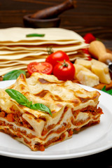 Portion of tasty lasagna on wooden backgound