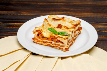 Portion of tasty lasagna on wooden backgound