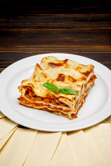 Portion of tasty lasagna on wooden backgound