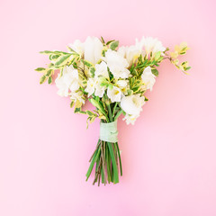 Wedding bouquet made of white flowers on pink background. Flat lay, top view. Wedding background.