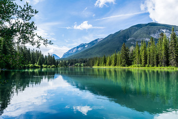 Canadian mountain scene with green lake reflections and blue sky