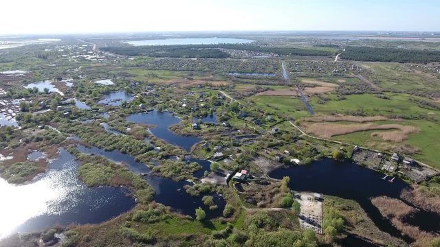 Amazing aerial shot of the Dnipro river with its little islets, curvy hook with indented coastline, straw looking grass, patches of greenary, and superb skyscape in Ukraine in a sunny day in spring