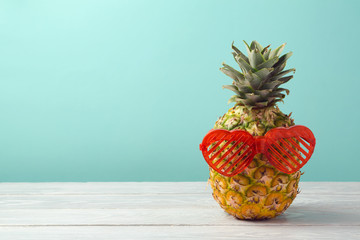Pineapple with party props glasses on wooden table over mint background. Tropical summer vacation  and beach party concept © maglara