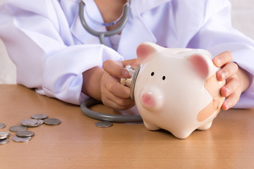 Asian girl playing as a doctor care Piggy Bank