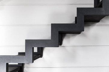 Stairs made of black metal over white wall