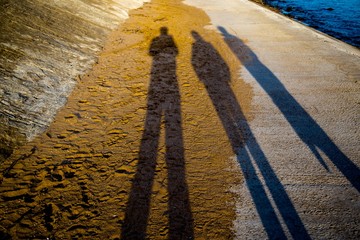 Three shadows from people on the beach at sunset