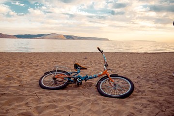 Fototapeta premium A bicycle lies on the sand on the river bank