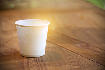 Fototapeta na wymiar paper cup on wooden table with sunshine and natural background