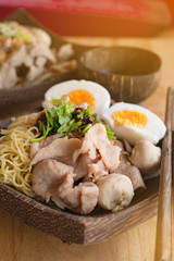 Low key of image of Meat Noodle with egg in a bowler bowl on wooden background. Thai Noodle small line with pork and meat ball. Favorite meal for lunch. Thailand food.
