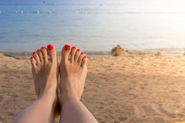 Vacation holidays. Woman feet closeup of girl relaxing on beach on sunbed enjoying sun on sunny summer day.
