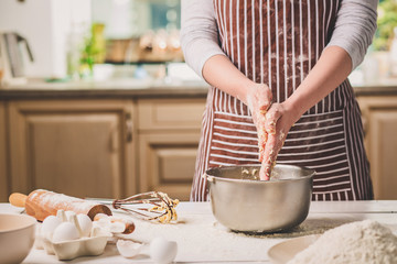 Woman hands kneading dough in iron bowl