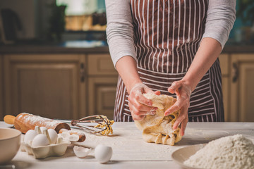 Woman hands kneading dough on kitchen table