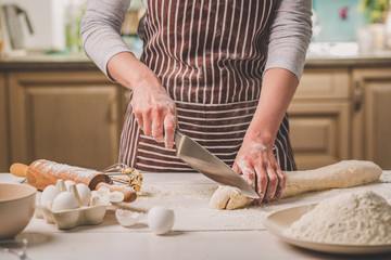 Obraz na płótnie Canvas Close-up view of two woman's hands cut knife dough
