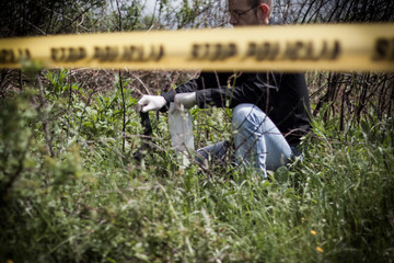 The crime scene, murder, investigation, police find rejected the gun used by the murderer, taken as evidence of the murder, an expert with rubber gloves and takes go in the bag as evidence