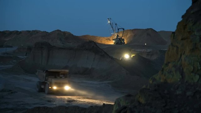 Excavators load ore into dump-trucks. This area has been mined for buaxite, aluminum and other minerals. Open-cast. Operating mine. Bauxite quarry at night.