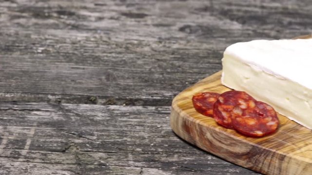 Sausage Chorizo, tomatoes, garlic bulb and a piece of Petite Brie cheese on the wooden desk