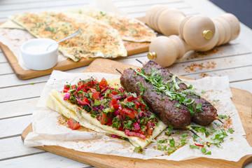 Kebab and Gozleme .Traditional oriental meat kebab of minced beef or lamb with vegetables and herbs overhead marble cutting boar. Gozleme with herb and cheese.