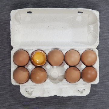 the A broken egg among whole eggs in an egg carton