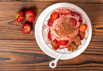 top view of dessert strawberry pink vanilla ice cream scoops with sprinkled chocolate and fresh strawberry on wooden table