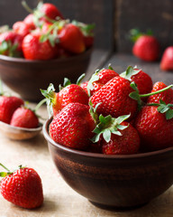 Fresh strawberry in a bowl on a wooden background