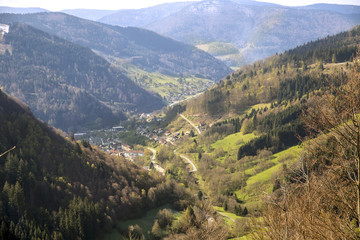 A green stretched out valley in the mountains of Germany with a winding road leading through