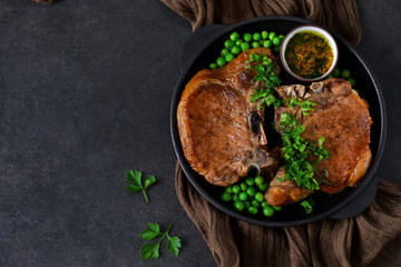 Steak grilled with a garnish of green peas and tomato sauce in a cast-iron frying pan