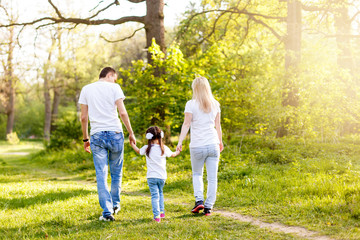 cute baby girl walking in park with parents