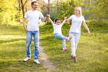 cute baby girl walking in park with parents