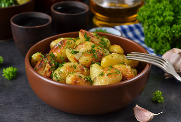 Young fried potatoes with garlic and dill on a black background