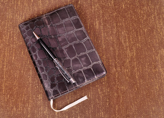 Notepad in leather cover on it pen on an abstract background
